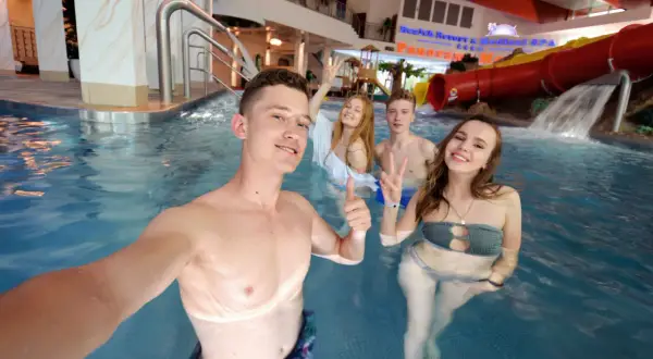 Grupa młodych ludzi w basenie. Czy osoba niepełnoletnia może wynająć pokój w hotelu? Zapytaj recepcję!
