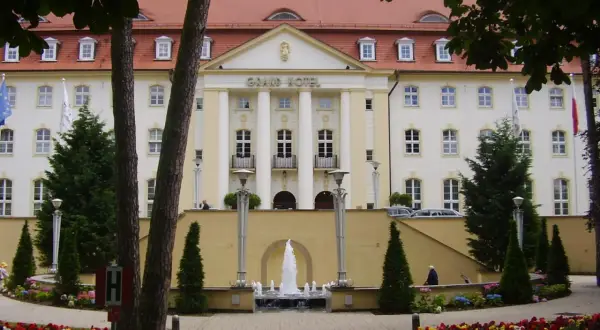 Grand Hotel z fontanną i ogrodem kwiatowym przed fasadą.