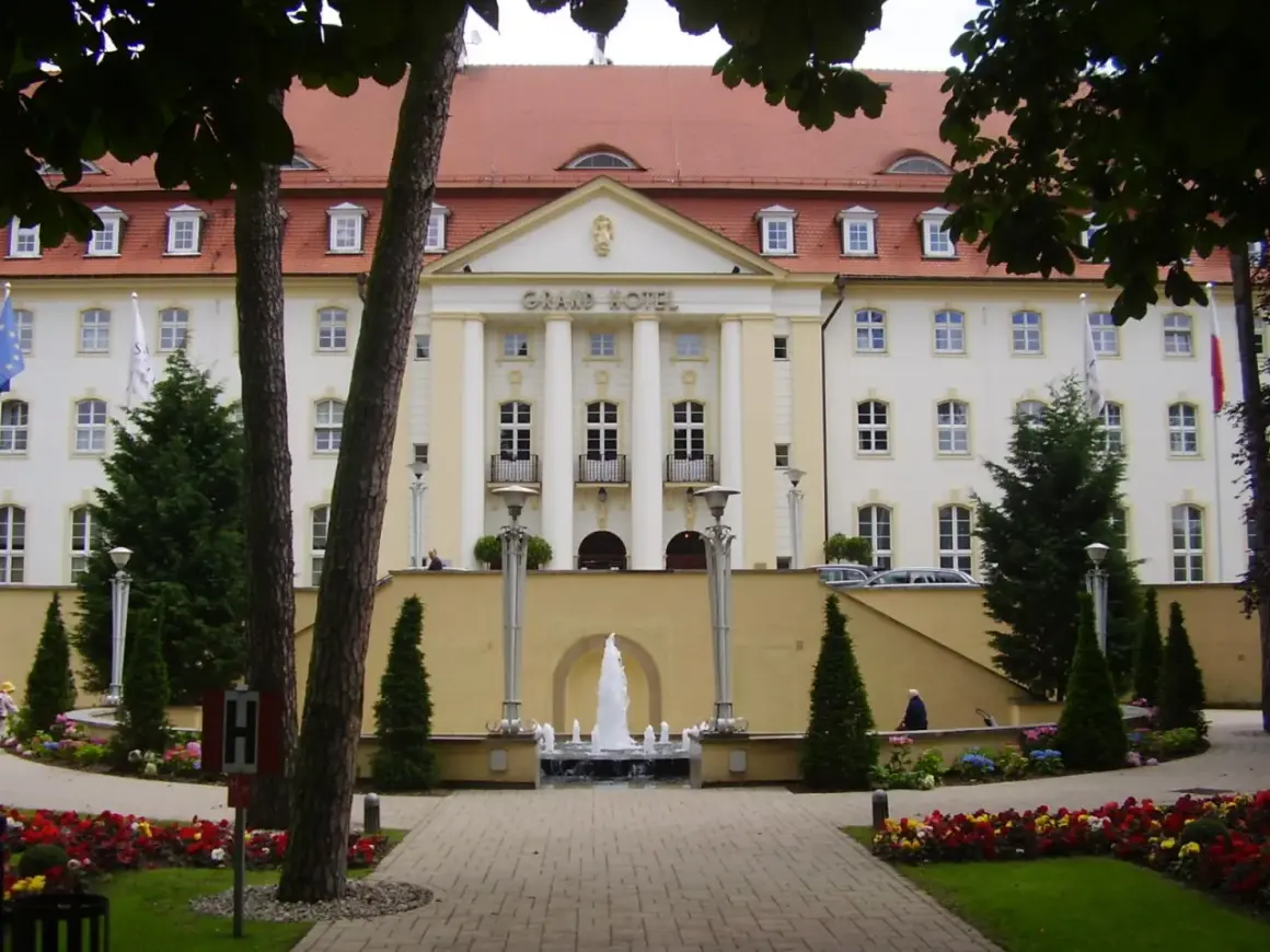 Grand Hotel z fontanną i ogrodem kwiatowym przed fasadą.